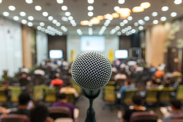 Microphone over a blurred photo of conference hall