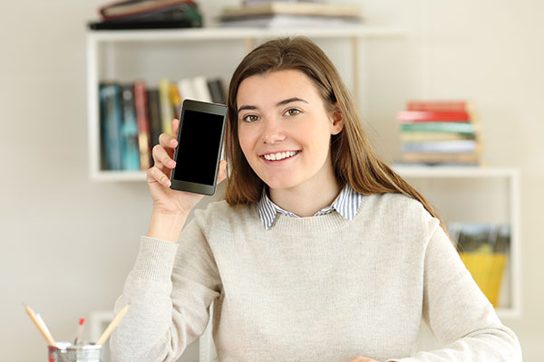 A happy female student showing a blank smart phone screen