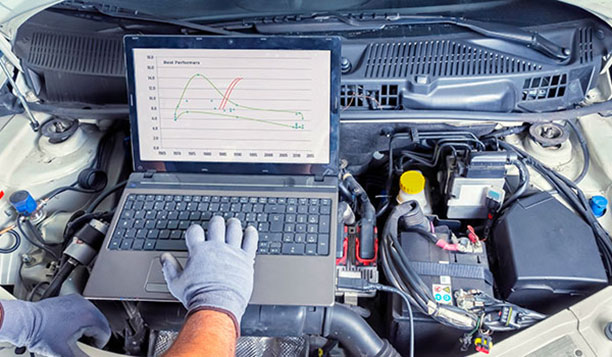 Person working on a laptop on top of a car engine