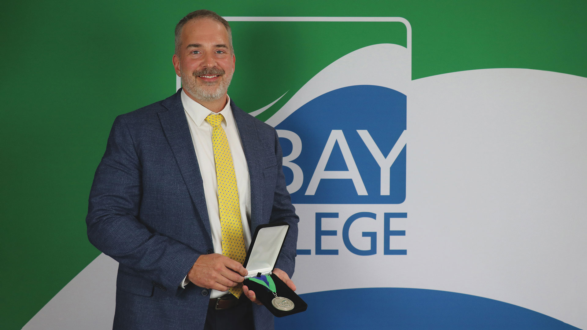 Bay College 2026 Distinguished Alumni of the Year Dr. Thad Strom, holding his award medallion.