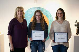 Instructor standing with two students holding scholarship awards