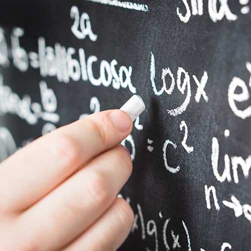 Close-up of a hand holding chalk writing on a chalkboard