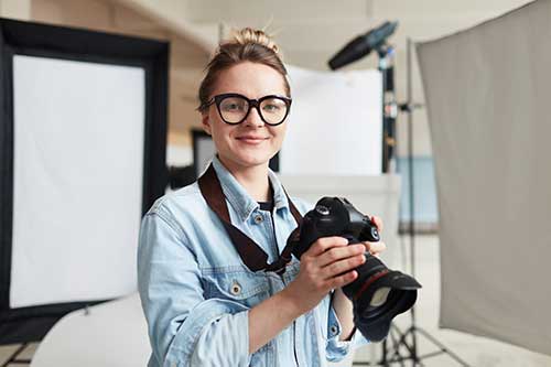 Male student smilingaFemale photographer holding camera in a studio.