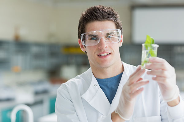 Student standing at the laboratory holding beaker with seedling