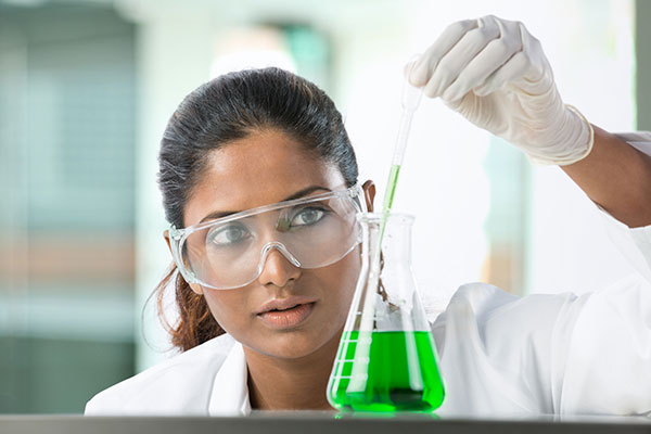 Female chemistry student analyzing a green solution