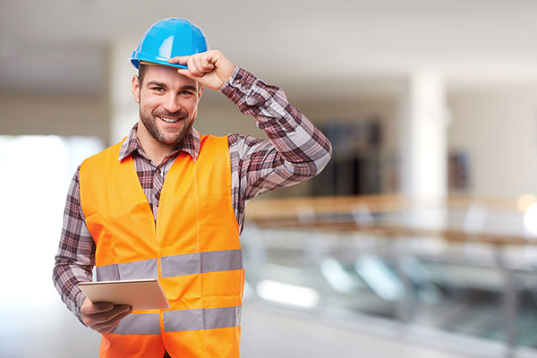 Smiling construction worker wearing an orange vest and blue hard hat