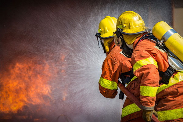 Two firefighters spraying high pressure water into a fire