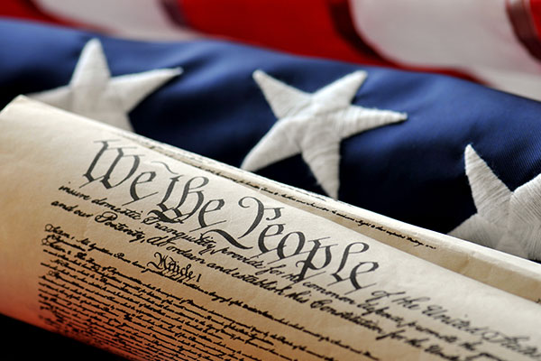 American Constitution with US Flag. Focus on document with stars and stripes in background.