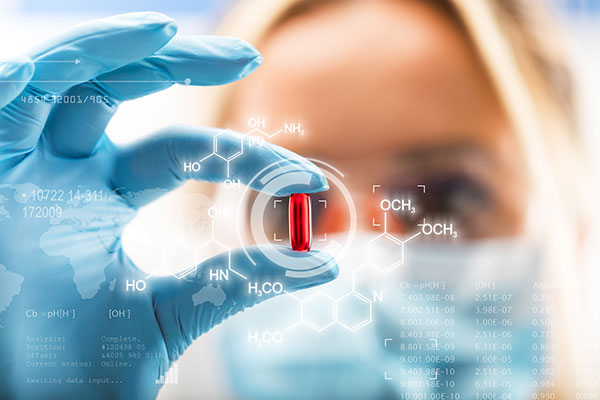 Female scientist holding a red transparent pill