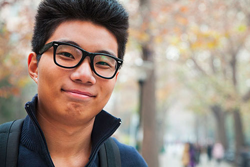 Smiling Asian college student wearing black glasses