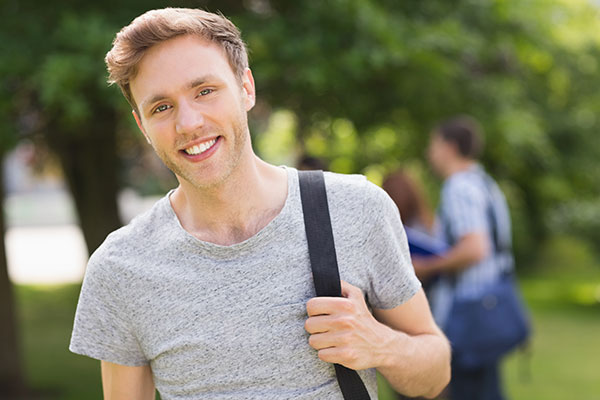 Male student smiling at camera outside on campus