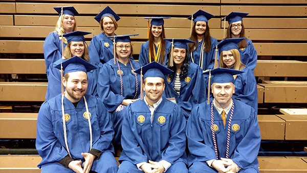 Graduates are pictured smiling in their blue caps and gowns.