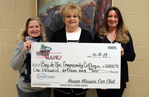 Kim Carne of Bay College is pictured smiling holding a large check along with Krusin Klassics representatives Janet Snowden and Michelle Oxford.