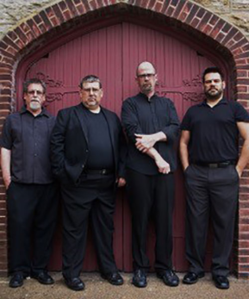 Members of Kind of Blues are pictured in black standing against a red background.