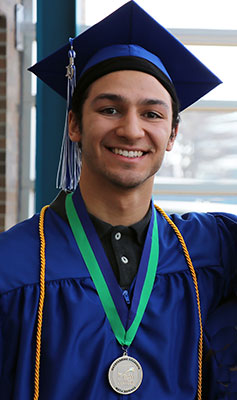 Dionte Malone is pictured in a black shirt and blue cap and gown and is wearing a medal