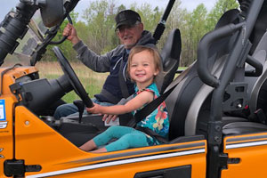 Bob Doepker sitting in a side-by-side ATV with grandaughter
