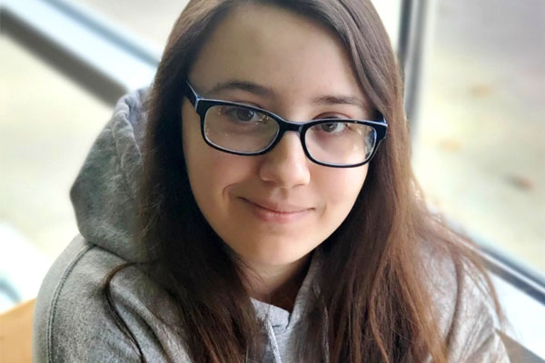 Young female college student smiling wearing glasses and hooded sweatshirt